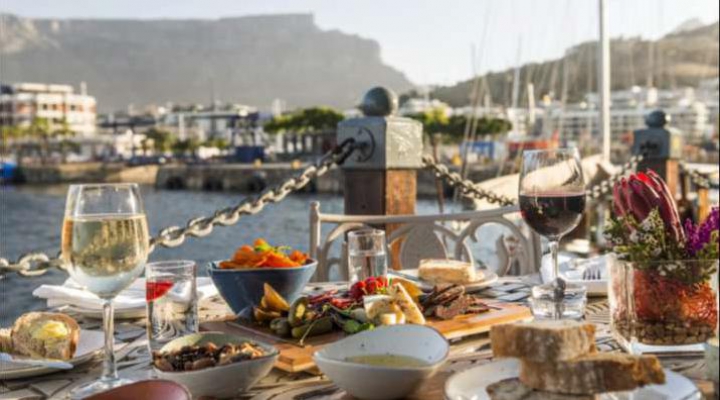 Al fresco waterfront dining with seafood dishes and wine glasses overlooking a marina