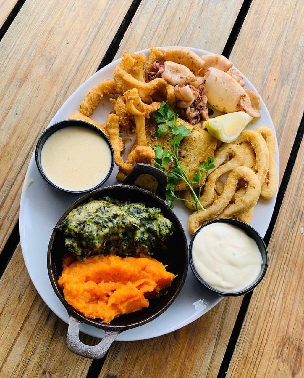 Seafood platter with fried calamari, two dipping sauces, creamed spinach and sweet potato mash