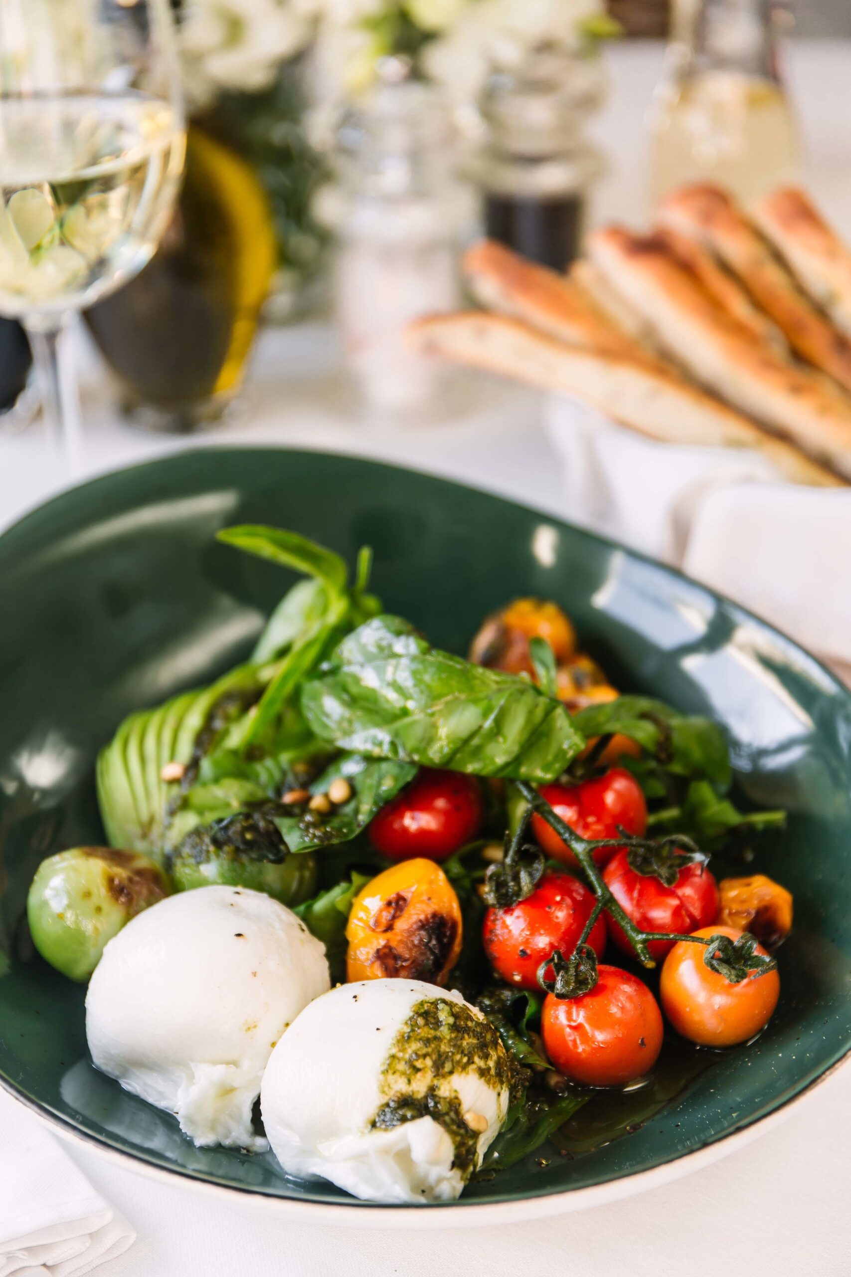 Burrata salad with blistered cherry tomatoes, avocado, greens and pesto