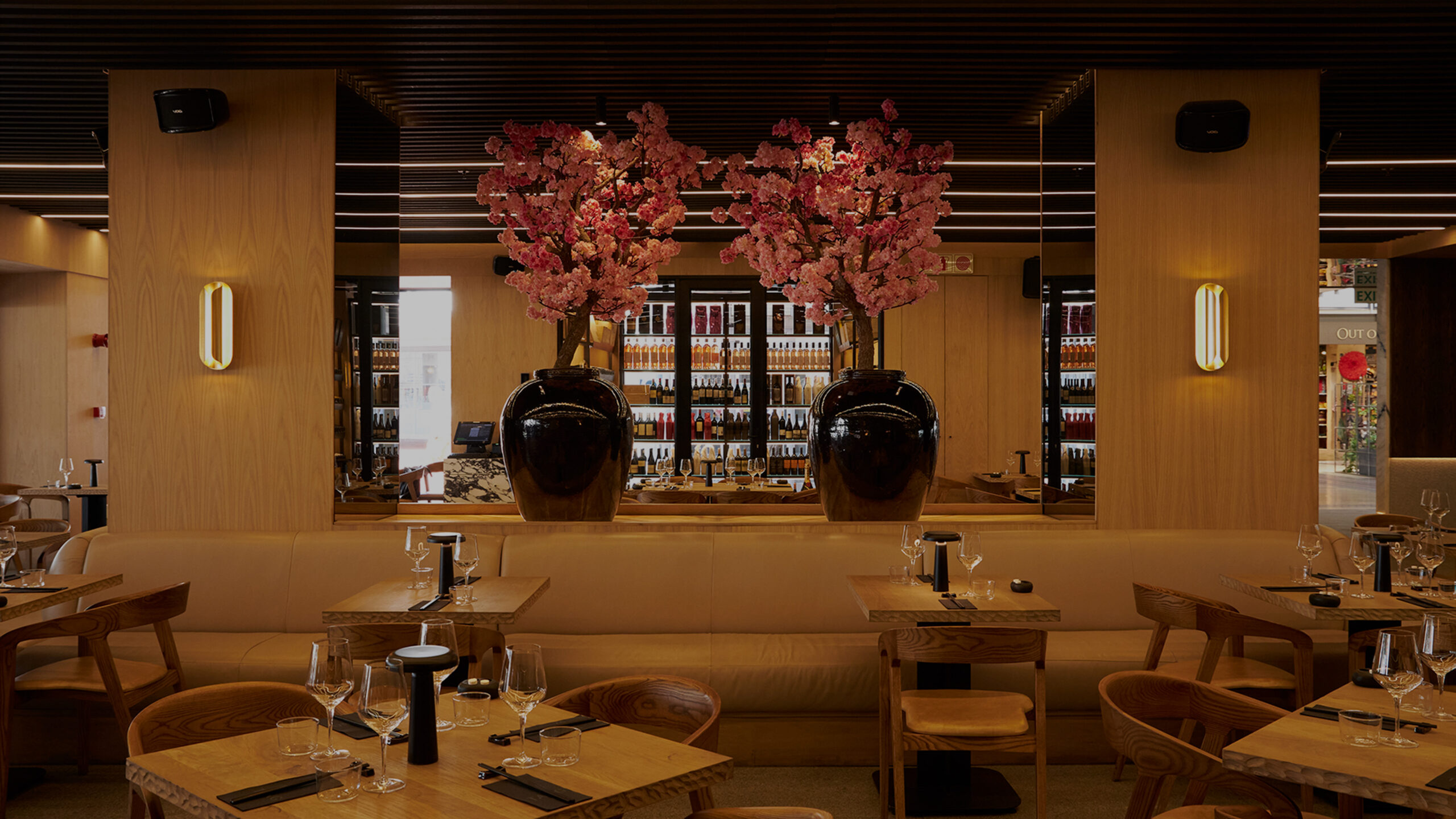 Upscale restaurant dining room with large vases of pink blossoms