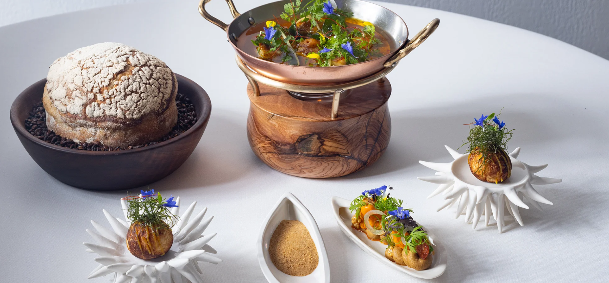 Artisanal bread, copper pot of herb broth and floral-garnished amuse-bouches