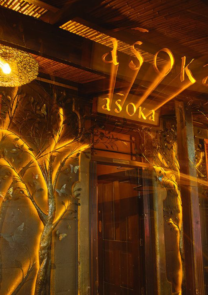 Asoka entrance with illuminated gold tree reliefs and warm amber lighting
