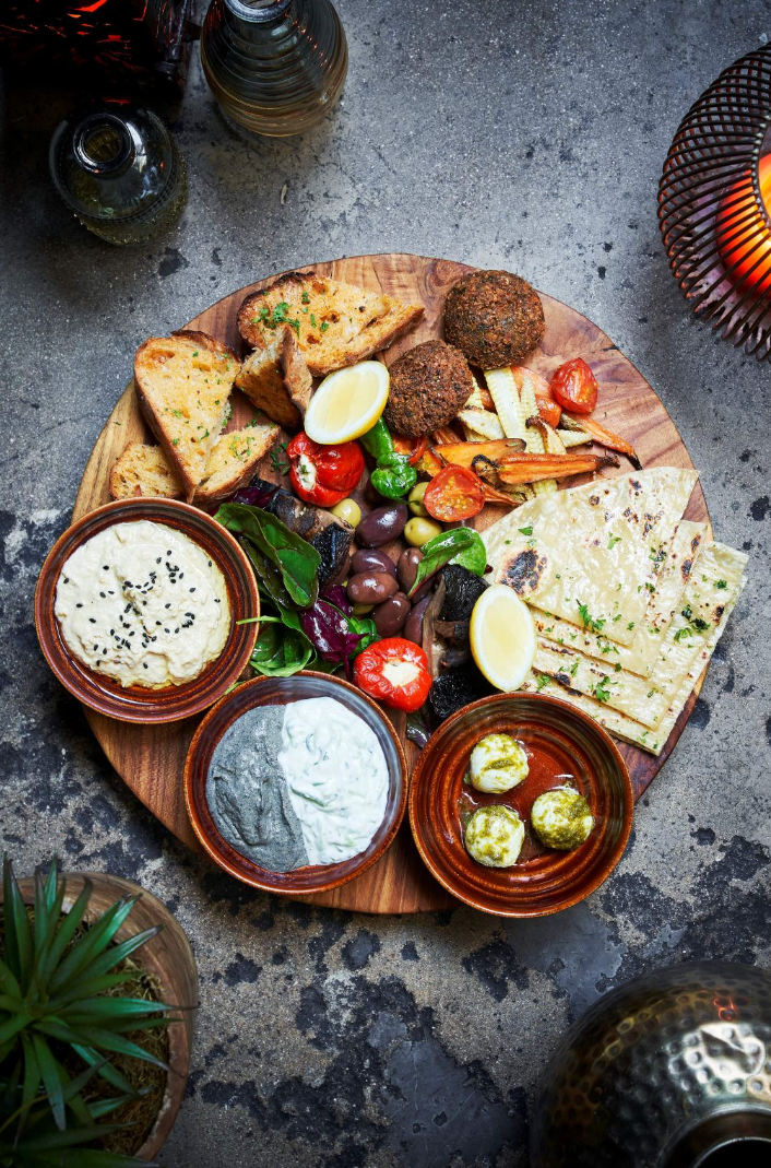 Mediterranean mezze platter with three dips, pita, olives, tomatoes, lemon and falafel