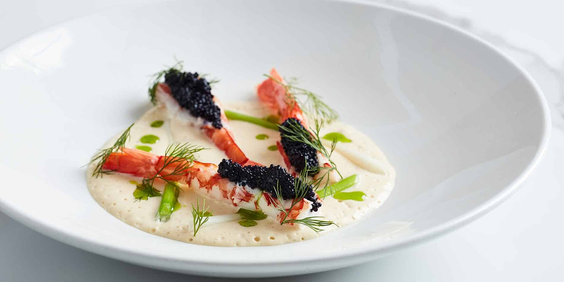Gourmet prawns topped with black caviar, herb oil and foam