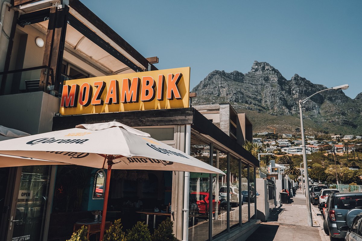 Mozambik restaurant sign and outdoor seating with mountain backdrop