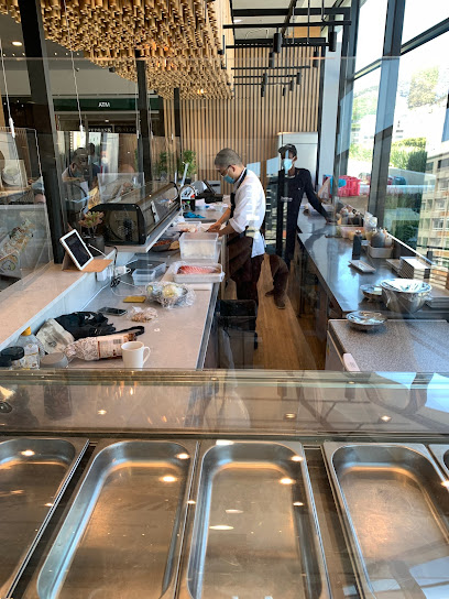 Sushi chef preparing rolls behind glass counter at Chef Chen Sushi Bar