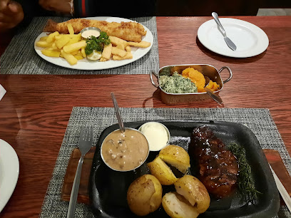 Cattle Baron Durbanville steak with roasted potatoes, mushroom gravy and fish-and-chips behind it
