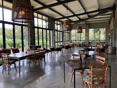 JÉAN Restaurant dining room with wooden tables, pendant lights and garden views