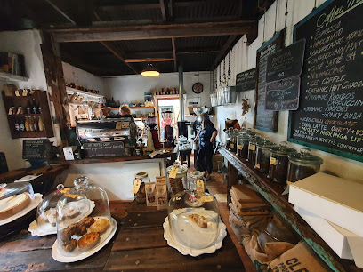 Houtbay Coffee interior with pastry display, barista, and chalkboard menu