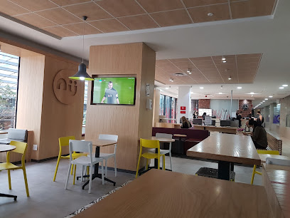 Nü Health Food Wembley café interior with tables, yellow chairs, customers and wall-mounted TV