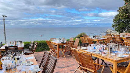 Black Marlin Restaurant terrace with wooden tables set for seaside dining in Simon's Town