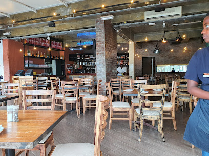 PRIMI Camps Bay dining area with wooden tables, bar and staff member