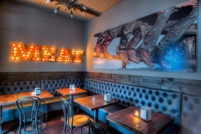 Cafe Manhattan interior with lit 'MEAT' marquee sign and tufted banquette seating