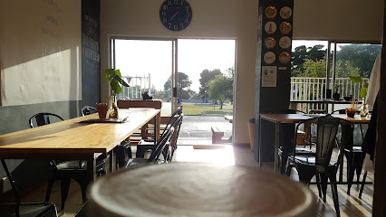 Boston Coffee Roasters interior: latte in foreground, sunlit tables and garden view
