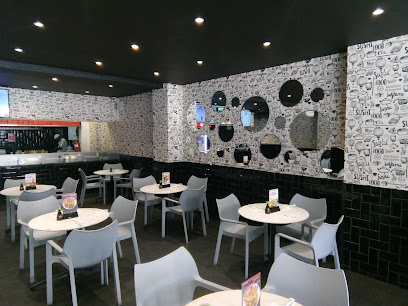 Nuri Sushi Factory Sea Point dining area with white tables, sushi-patterned wall