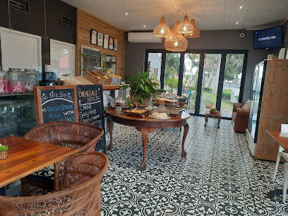 Lorenzo Marx Coffee Bar Paardevlei interior — central pastry table, rattan seating, patterned tile floor