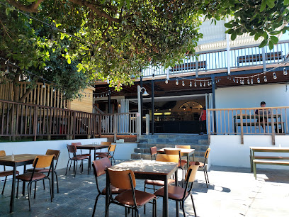 Outdoor courtyard seating at Aegir Project Brewery Noordhoek with tables under trees
