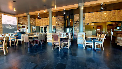 Bossa Somerset West dining area with wooden tables, bar and brick walls