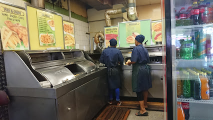 Two Super Fisheries staff working at stainless-steel fryers under menu boards