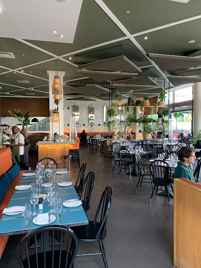 NV-80 Grill & Bar interior with set tables, bar, and hanging plants