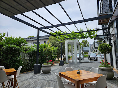 Simply Eat Firgrove outdoor dining area with wooden tables, white chairs, pergola