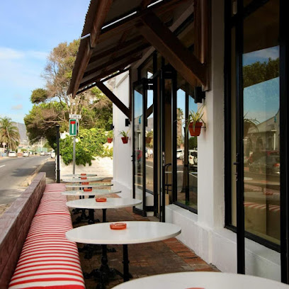 Outdoor seating at Pizza Shed St James with red-striped bench and round marble tables