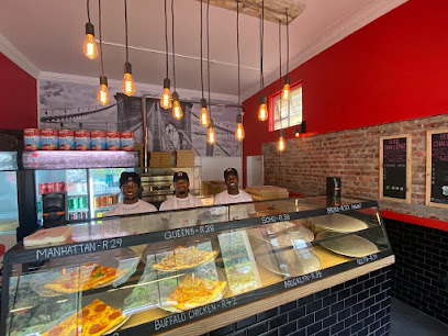 NY Slice Pizza Muizenberg counter with three staff and labeled pizza slices