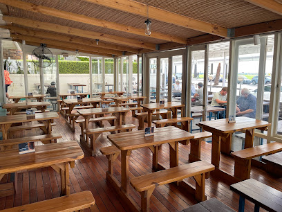 Rockpool Cape Town indoor dining area with wooden bench tables and glass walls