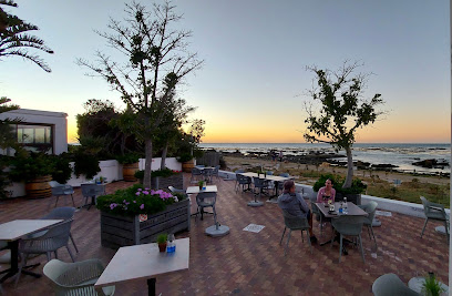 Outdoor seaside terrace at The Melkbos Kitchen with diners at sunset
