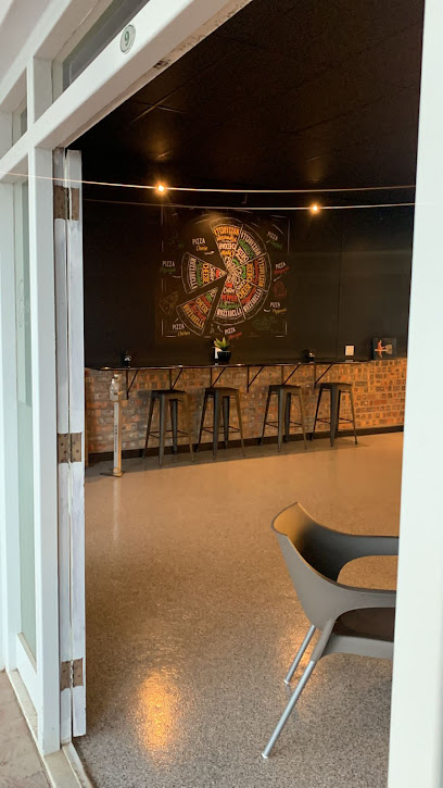Berlinos Woodfired Pizza interior — brick counter, bar stools, chalkboard pizza wheel