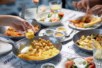 Ocean Basket Durbanville seafood spread with pans of rice, prawns, and sauces