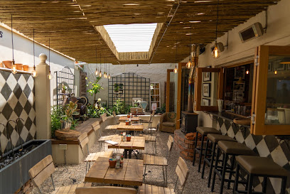 Hans & Lloyd Coffee Co Newlands shaded patio with wooden tables and potted plants