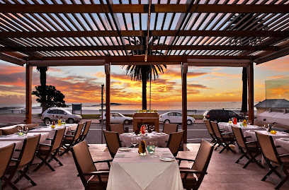 Paranga outdoor dining terrace at sunset with ocean view and set tables