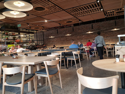 Woolworths Café Village Square interior with wooden tables, diners, exposed brick