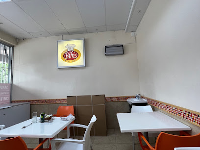 Bibis Kitchen interior with illuminated wall logo, white tables and orange chairs