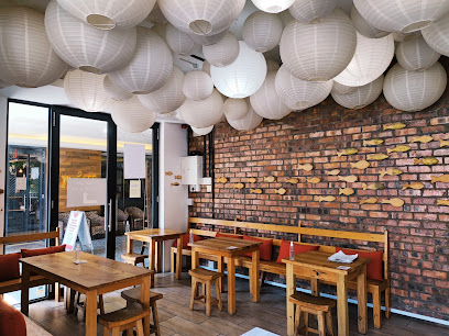 Sushi Box De Waterkant dining area with wooden tables, bench seating and white paper lanterns