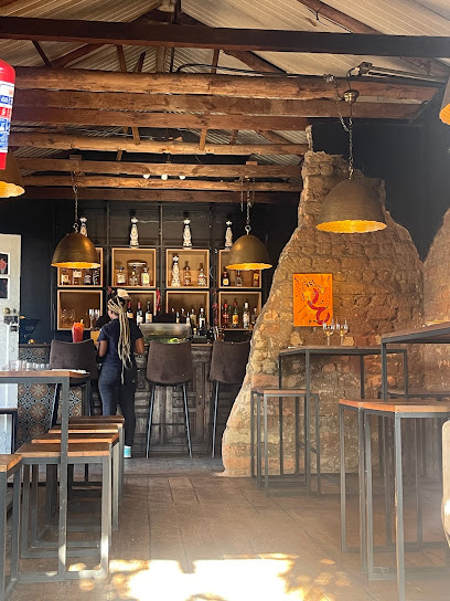 Mexicola Locale interior with bar counter, pendant lights, stone wall and high tables