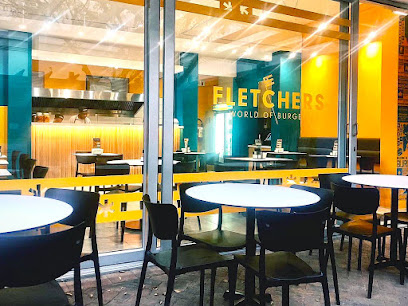 Fletcher's Burgers storefront with outdoor tables and lit interior seating
