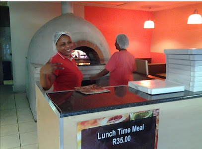 Dial A Pizza staff by wood-fired oven preparing pizzas behind counter