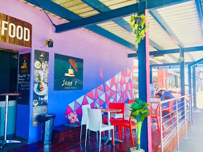 Joka's Good Food outdoor seating with colorful purple mural and tables