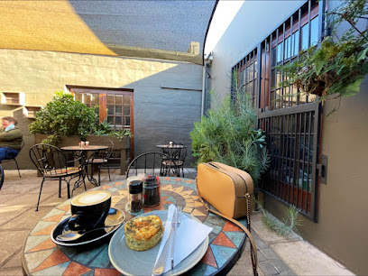 All in the Kitchen Deli patio table with coffee, savory tart and tan bag