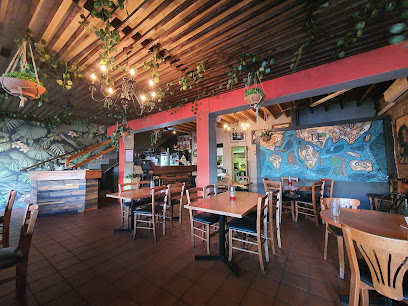 Jamaica Me Crazy interior with Caribbean mural, hanging plants and wooden tables