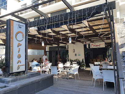 The Orient outdoor dining deck with white chairs and diners
