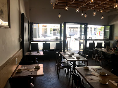 Interior of Make Restaurant Sea Point with set wooden tables and front windows