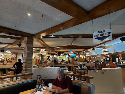 Spur restaurant dining room with booths, hanging lamps, diners and 'PLEASE MIND THE STEP' sign