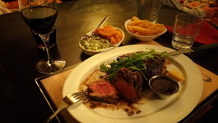 Sliced medium-rare steak with sauce, salad and fries, and red wine at Nelson's Eye Restaurant
