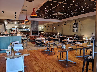 GREENS Plattekloof dining area with wooden tables and open kitchen