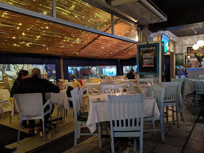 Mykonos Taverna Sea Point outdoor dining area with white tables, candles and string lights
