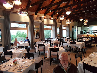 Cassia Restaurant dining room with white-tablecloth tables, wooden-beamed ceiling and pendant lights