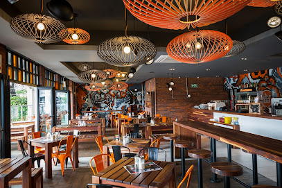 RocoMamas Durbanville interior with pendant lights, wooden tables and orange chairs